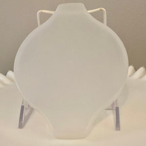 May include: A white frosted glass cake plate with a rounded edge and a smooth surface. The plate is on a clear plastic stand.