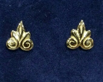 Könnte beinhalten: Ein Paar goldfarbene Ohrringe mit einem zarten, verzierten Design. Jeder Ohrring hat eine stilisierte Blattform mit einem Doppelwirbelmuster.