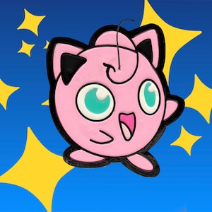 May include: A pink, round, cartoon-style character pin with large teal eyes, a small mouth, and pointed ears with black accents. The character features a single curled hair strand on top and is outlined in black, set against a blue background with yellow stars.