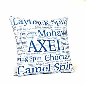 May include: White throw pillow with a blue word cloud design featuring various figure skating terms, including "Layback Spin", "Axel", "Camel Spin", and "Choctaw".