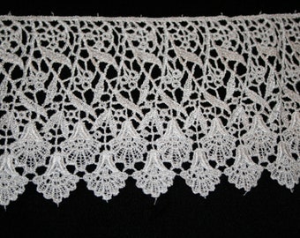 May include: White lace trim with a scalloped edge and a delicate floral pattern. The lace is made of a fine, lightweight material and has a soft, flowing texture.