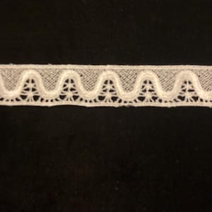 May include: White cotton lace trim with a scalloped edge and a delicate floral pattern.