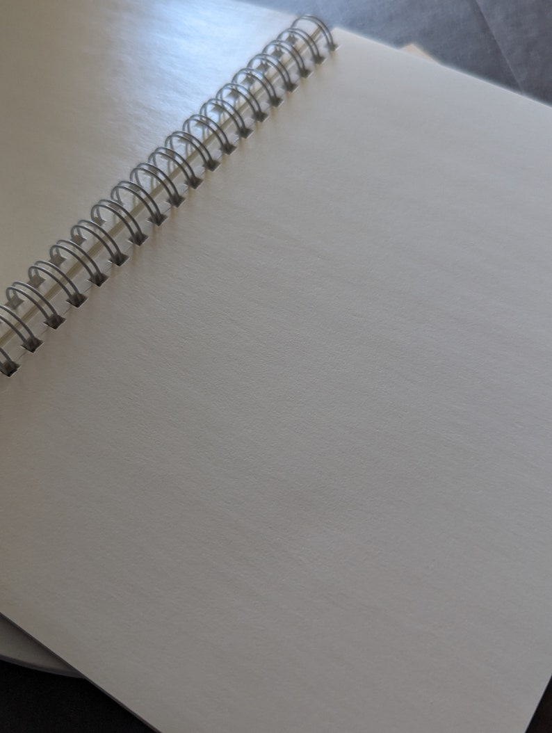 May include: A white spiral bound notebook with a silver binding.
