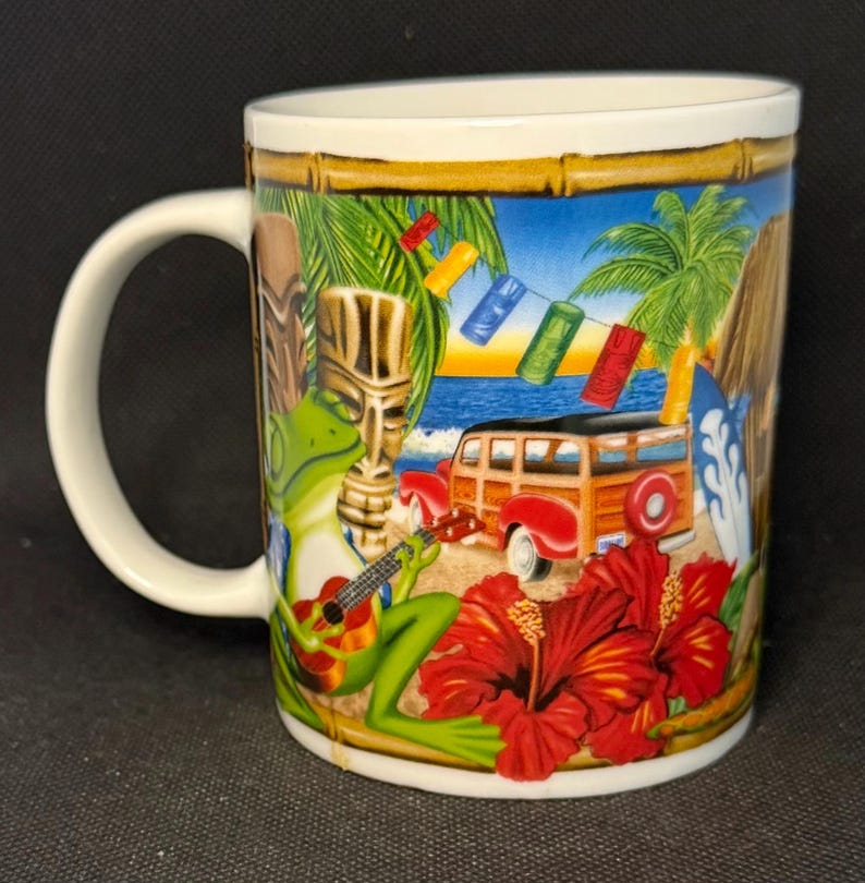K&ouml;nnte beinhalten: Ein wei&szlig;er Keramikbecher mit einer farbenfrohen tropischen Szene, die einen gr&uuml;nen Frosch beim Gitarrespielen, eine h&ouml;lzerne Tiki-Statue, einen roten Kombi, Palmen, rote Hibiskusbl&uuml;ten und eine Lichterkette mit kleinen Tiki-Masken zeigt.