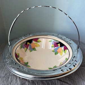May include: A silver bowl with a floral design and a silver handle. The bowl is on a white background.