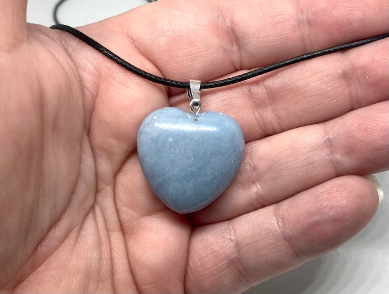 K&ouml;nnte beinhalten: Halskette mit hellblauem herzf&ouml;rmigem Anh&auml;nger. Der Anh&auml;nger besteht aus einem glatten, polierten Stein und h&auml;ngt an einer schwarzen Kordel. Der Anh&auml;nger ist etwa 3,8 cm breit.