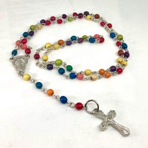 May include: A colourful wooden bead rosary with a silver cross pendant. The beads are arranged in a rainbow pattern.