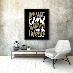 Puede incluir: Póster de tipografía en blanco y negro con el texto "No te canses de hacer el bien" con la referencia bíblica "Gal 6:9" en una fuente más pequeña debajo. El póster está enmarcado en negro y colgado en una pared de concreto gris.