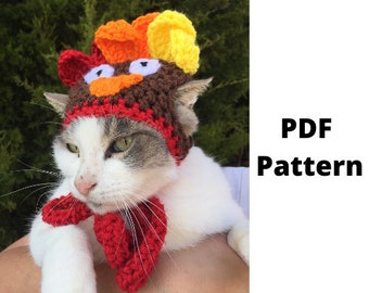 May include: A cat wearing a handmade crochet turkey hat and matching red scarf. The hat features brown, red, orange, and yellow yarn, with white eyes and an orange beak. The text "PDF Pattern" is visible.