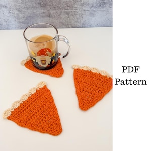 May include: Three orange crochet coasters shaped like pie slices with a beige scalloped edge. One coaster is under a clear glass mug with a gnome design. The text "PDF Pattern" is visible.