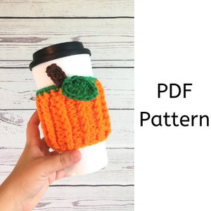 May include: Crochet pumpkin coffee cup cozy pattern in PDF format. The cozy is orange with a green stem and leaf.