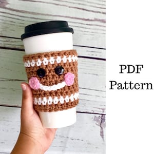 Pode incluir: Capa de crochet para caneca de café em forma de homem de gengibre com listras brancas e marrons, bochechas cor-de-rosa e olhos pretos. Padrão PDF.