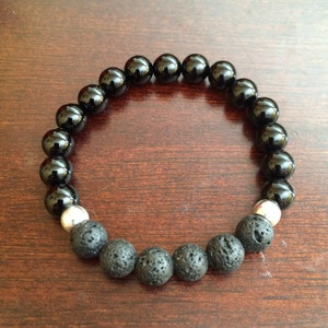 Puede incluir: Pulsera de cuentas negras con cuentas de lava negra y cuentas espaciadoras plateadas.
