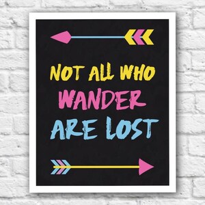 May include: Black and white printable wall art with the quote "Not all who wander are lost" in colorful text. Two arrows with yellow, pink, and blue accents are on either side of the quote.