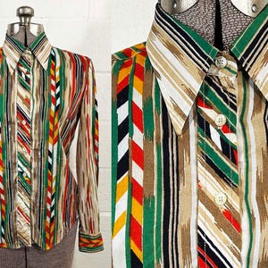 May include: A vintage button-down shirt with a colorful striped pattern. The shirt features vertical stripes in shades of green, red, yellow, brown, and white. It has a collared neckline and long sleeves. The shirt is displayed on a mannequin.