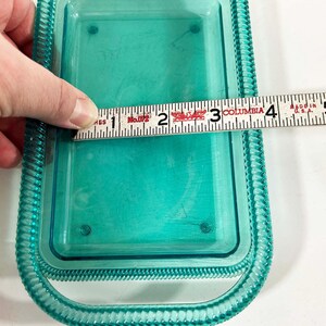 May include: A turquoise blue plastic dish with a decorative border. The dish is 4 inches wide.