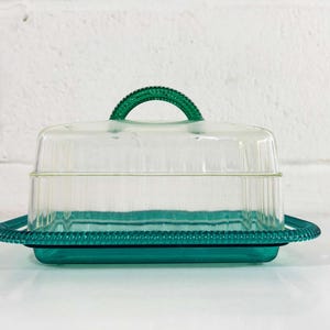 May include: A clear glass butter dish with a green lid and base. The lid has a green handle.