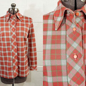 May include: A vintage button-down shirt in a plaid pattern of coral, light blue, and green. The long-sleeved shirt features a pointed collar and matching coral buttons. The shirt is displayed on a mannequin.