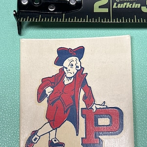 May include: A vintage sticker featuring a cartoon illustration of a man wearing a red coat and a blue hat, standing next to a large red letter "P".