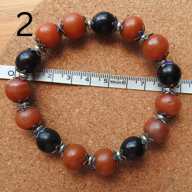 May include: A bracelet made of brown and black beads with silver accents. The bracelet is approximately 6 inches in length.