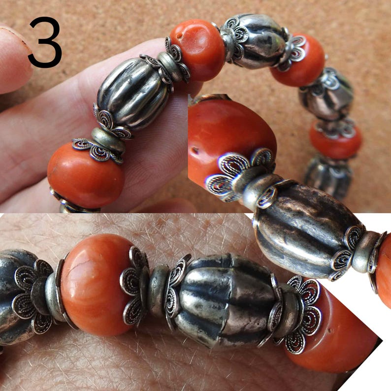 May include: A bracelet made of red coral beads and silver beads with intricate filigree designs. The bracelet is on a person's wrist.