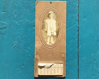 Calendário de estúdio fotográfico de 1912 com criança, no estado em que se encontra.