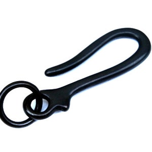 May include: Black metal key chain hook with a ring. The hook is shaped like a letter S and has a rounded end. The ring is attached to the hook at the top.