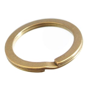 Pode incluir: Um chaveiro de metal dourado com uma superfície lisa e arredondada. O anel está aberto de um lado, permitindo que as chaves sejam anexadas.