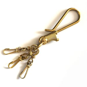 May include: A gold-toned metal key chain with a large loop and three smaller loops. The key chain is made of twisted wire.