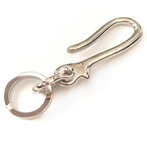 Op de afbeelding: Zilveren sleutelhanger met een haak en een ring. De haak is gebogen en de ring is rond.