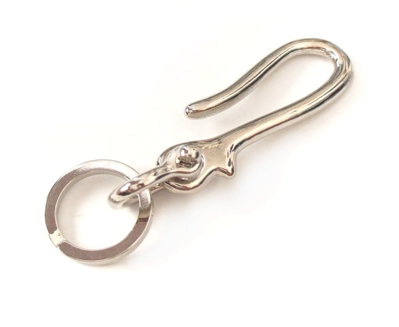 Op de afbeelding: Zilveren sleutelhanger met een haak en een ring. De haak is gebogen en de ring is rond.