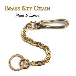 Könnte beinhalten: Ein Schlüsselanhänger aus Messing mit Hakenverschluss und Kette aus ineinandergreifenden Gliedern. Er enthält einen Schlüsselring. Der Text "BRASS KEY CHAIN" und "Made in Japan" ist im Bild zu sehen.