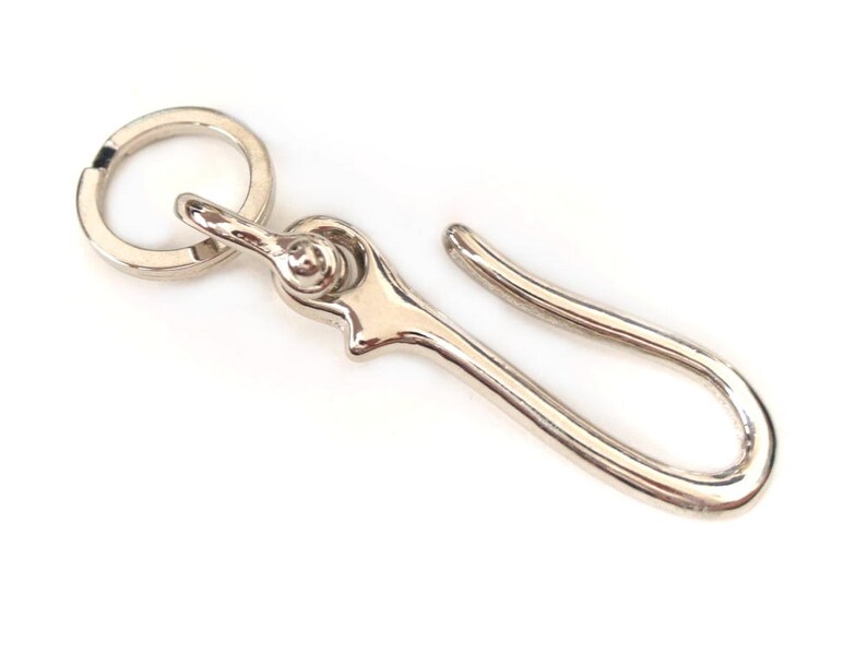 Op de afbeelding: Zilveren sleutelhanger met een ronde ring en een haak. De haak is gebogen.