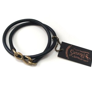 Puede incluir: Pulsera de cuero negro con cierre de s&iacute;mbolo de infinito de lat&oacute;n. La pulsera est&aacute; envuelta dos veces y tiene una peque&ntilde;a etiqueta adjunta que dice "Guaranteed - Sasori - Trademark - Old Valley Tokyo".