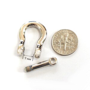 K&ouml;nnte beinhalten: Ein gl&auml;nzendes, silberfarbenes Sch&auml;kel mit einer 7 mm &Ouml;ffnung, neben einer 10-Cent-M&uuml;nze. Der Sch&auml;kel ist U-f&ouml;rmig mit einem Schraubbolzen. Die M&uuml;nze zeigt das Profil von Franklin D. Roosevelt.