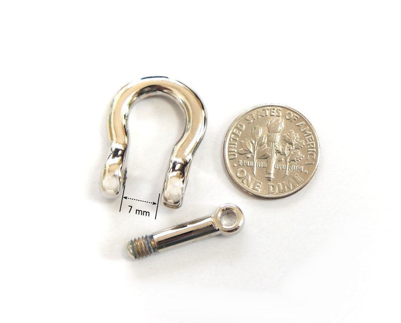 K&ouml;nnte beinhalten: Ein gl&auml;nzendes, silberfarbenes Sch&auml;kel mit einer 7 mm &Ouml;ffnung, neben einer 10-Cent-M&uuml;nze. Der Sch&auml;kel ist U-f&ouml;rmig mit einem Schraubbolzen. Die M&uuml;nze zeigt das Profil von Franklin D. Roosevelt.