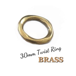 May include: A brass twist ring, approximately 1.18 inches in diameter, with a unique twisted design. The ring is a warm gold color and is set against a white background. The text "30mm Twist Ring BRASS" is below the ring.