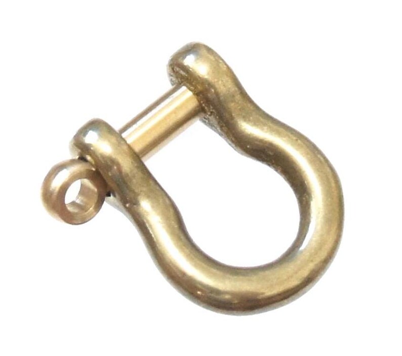 May include: A gold-colored metal u-shaped clasp with a pin. The clasp is smooth and shiny.