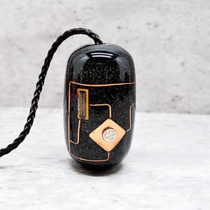May include: A black and gold mouse with a circuit board design and a small battery on the side. The mouse is attached to a black cord.