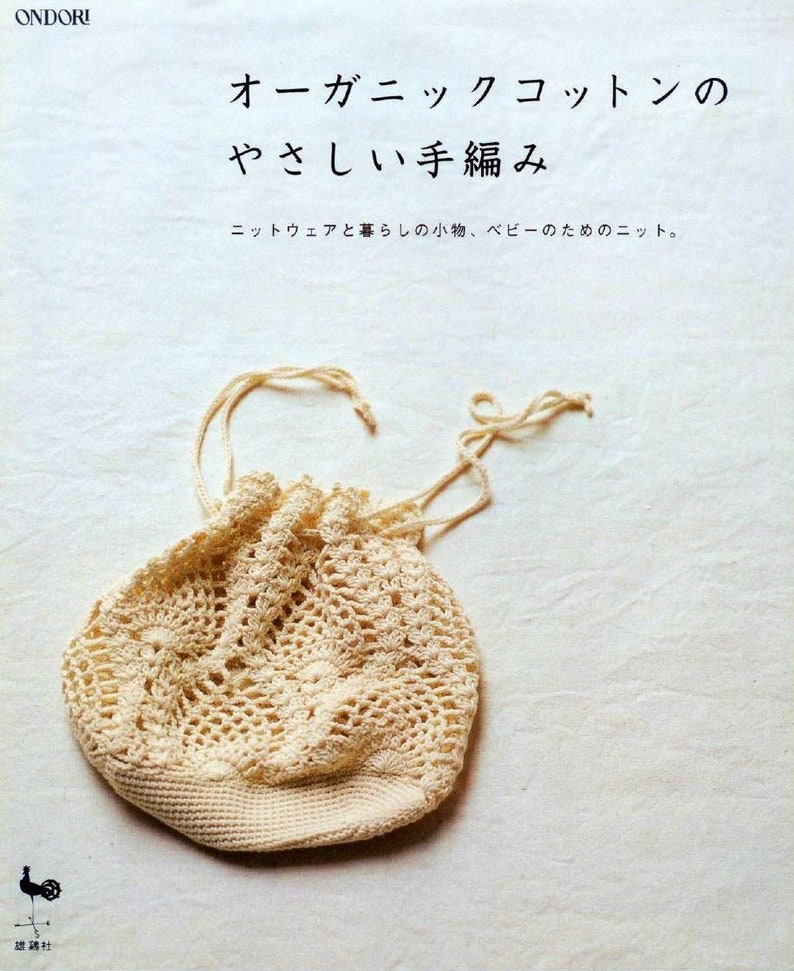 May include: A close-up of a crocheted drawstring bag made from organic cotton. The bag is a light beige colour and has a delicate, lacy pattern. The bag is lying on a white fabric surface.