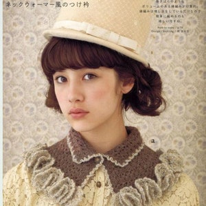 May include: A woman wearing a white hat with a brown crocheted collar. The collar has a ruffled edge and is made with a delicate stitch. The text "ネックウォーマー風のつけ衿" is visible in the image.