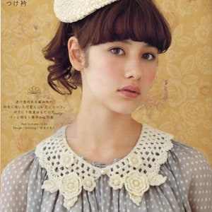 May include: A white crocheted collar with a delicate floral design. The collar is worn over a grey polka dot blouse. The text "アイリッシュ クロッシェレースの つけ衿" is visible in the image.