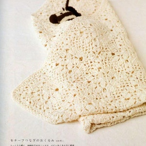 May include: A white crocheted baby blanket with a small stuffed zebra toy inside. The blanket is made with a delicate stitch pattern and has a soft, fluffy texture.