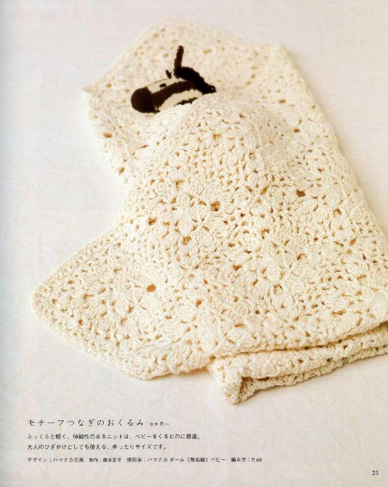 May include: A white crocheted baby blanket with a small stuffed zebra toy inside. The blanket is made with a delicate stitch pattern and has a soft, fluffy texture.