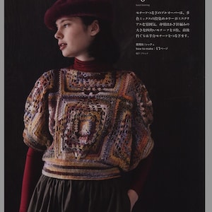 May include: A crocheted top with a multi-colored geometric pattern. The top has a round neckline and short sleeves. The model is wearing a burgundy beret and a dark green skirt.