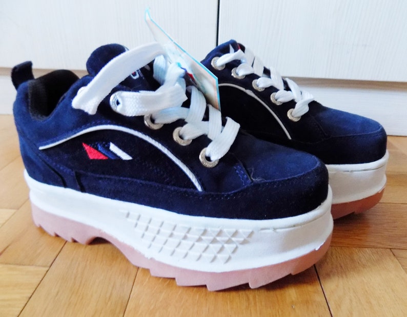 May include: A pair of navy blue platform sneakers with white laces and a white sole. The sneakers have a pink outsole and a small logo with red, white, and blue accents. The shoes are new with tags.