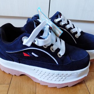 May include: A pair of navy blue platform sneakers with white laces and a white sole. The sneakers have a pink outsole and a small red and white design on the side. The shoes are new and have a tag attached.