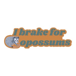 Op de afbeelding: Een gestanste sticker met een illustratie van een grijs en wit opossum aan de linkerkant. De tekst "I brake for opossums" is geschreven in een vet, donkerblauwgroen lettertype op een effen, afgeronde oranje achtergrondvorm.