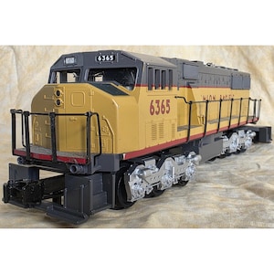 May include: A model Union Pacific locomotive, painted in yellow and gray, with the number 6365 displayed prominently. The model train features detailed wheels, railings, and the words "UNION PACIFIC". The model train is a collectible item.