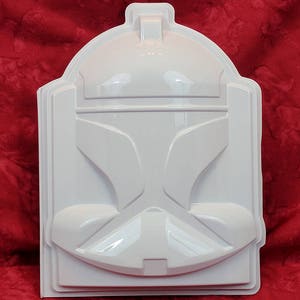 May include: White plastic mold of a Star Wars Clone Trooper helmet. The mold is detailed with the helmet's features, including the visor and the helmet's ridges.
